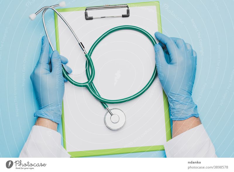 female doctor's hands in blue latex gloves holding a metal stethoscope paper surgeon tool treatment clipboard woman worker disease professional adult cardiology
