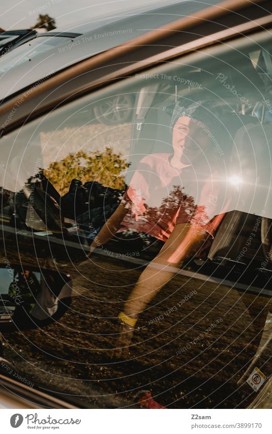 Young woman in car photographed through window Summer Sun Light reflection Motoring Mobility Window pane Nature Driving Car Vehicle Laughter Woman feminine