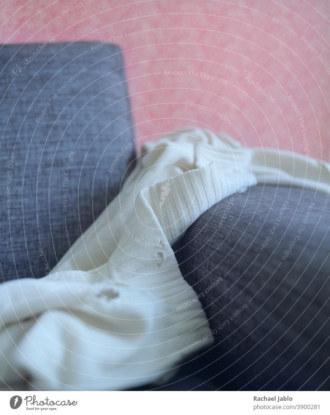 Motheaten white sweater on sofa moth holes pink rustic close-up macro still-life