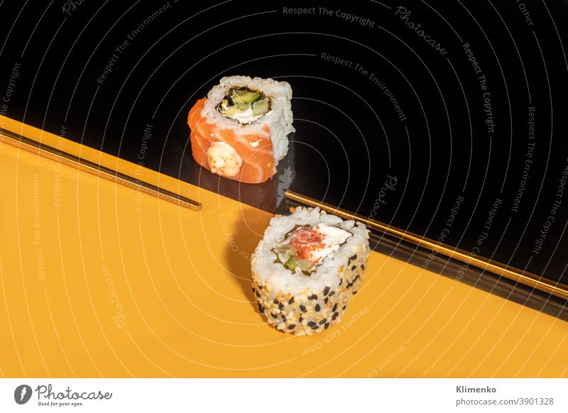 Sushi Sets Uramaki, California, Philadelphia, on a white plate. Festive, New Year concept. Against a dark reflective background. sushi red new year order