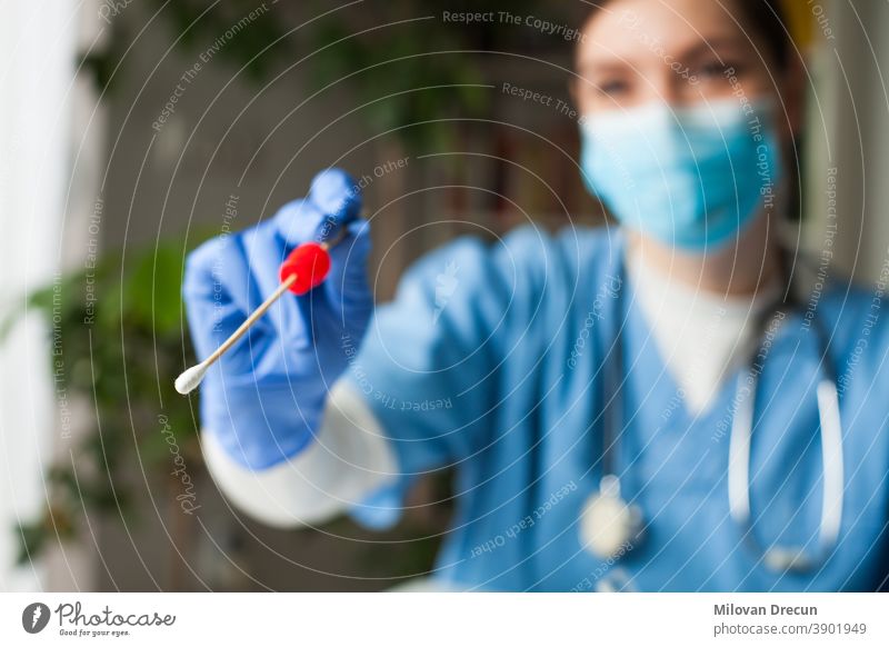 Female caucasian NHS doctor holding a swab collection stick, nasal and oral specimen swabbing in doctor's office, patient PCR testing procedure appointment, Coronavirus COVID-19 global pandemic crisis