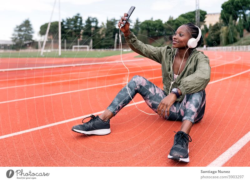 Athlete sprinter sitting listening to music smartphone afro concentration technology cell cellphone helmet mobile athlete ethnic afroamerican track train