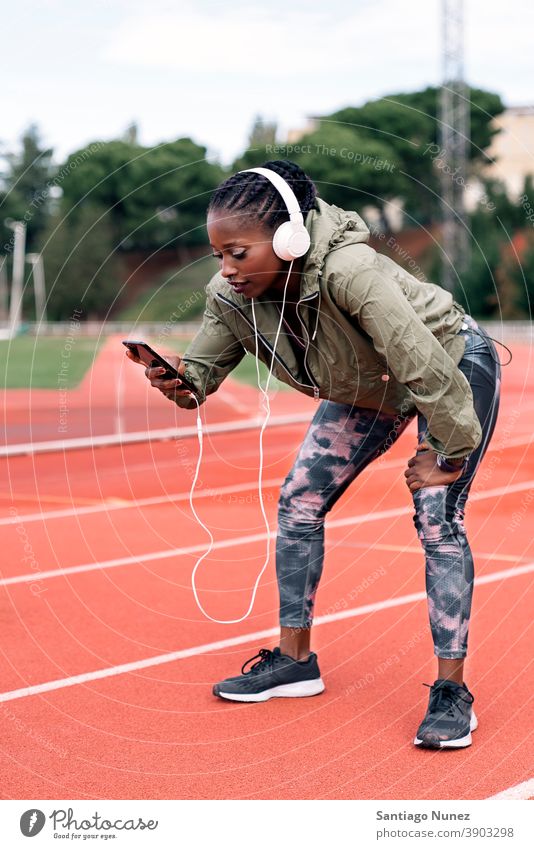 Athlete sprinter listening to music exhausted smartphone afro concentration technology cell cellphone helmet mobile athlete ethnic afroamerican track train