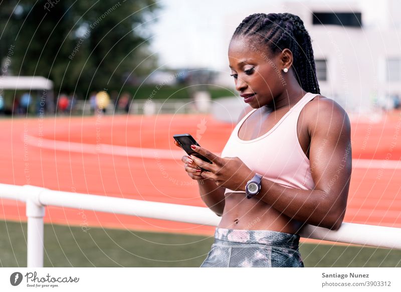 Athlete sprinter supported using mobile phone smartphone afro technology cellphone athlete ethnic afroamerican track train training sportswear athleticism
