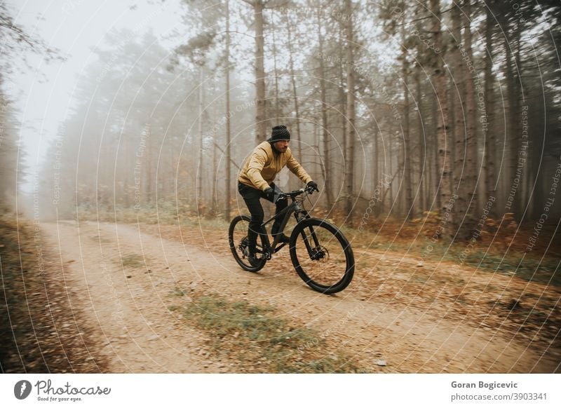 Young man biking through autumn forest bicycle bike nature ride cyclist biker lifestyle outdoor sport exercise trail mountain action extreme recreation tree