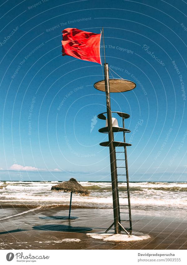 Lifeguard tower with flag on seashore lifeguard rescue beach seaside wave symbol summer seascape ocean observe coast coastline season seacoast blue sky