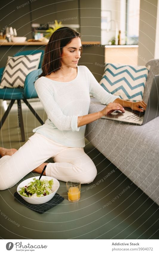 Young woman eating salad and working on laptop at home healthy young gadget food female casual lifestyle internet online using meal connection rest weekend
