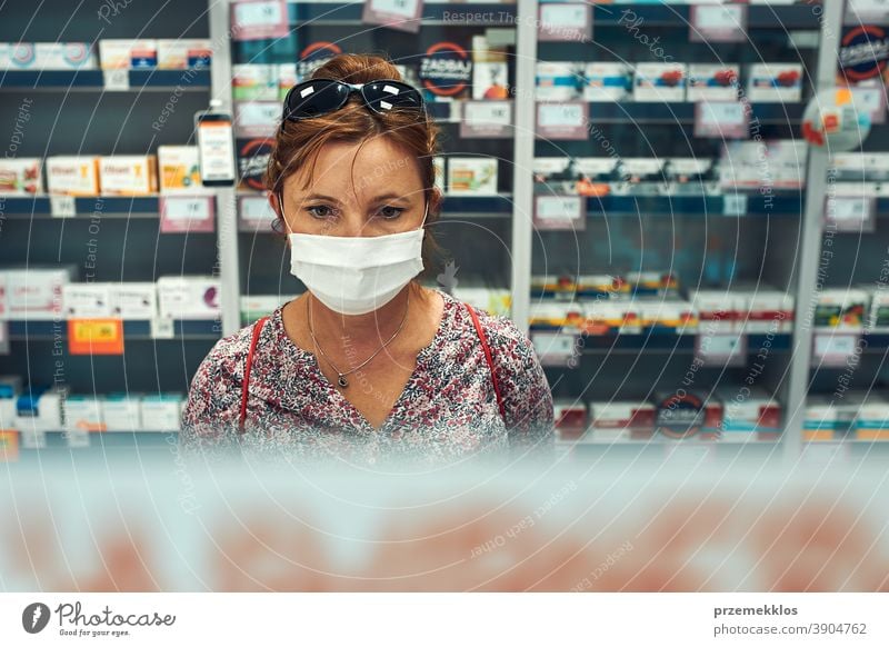 Woman shopping at pharmacy, buying medicines, wearing face mask during pandemic coronavirus outbreak woman chemist covid-19 cover standing town female care