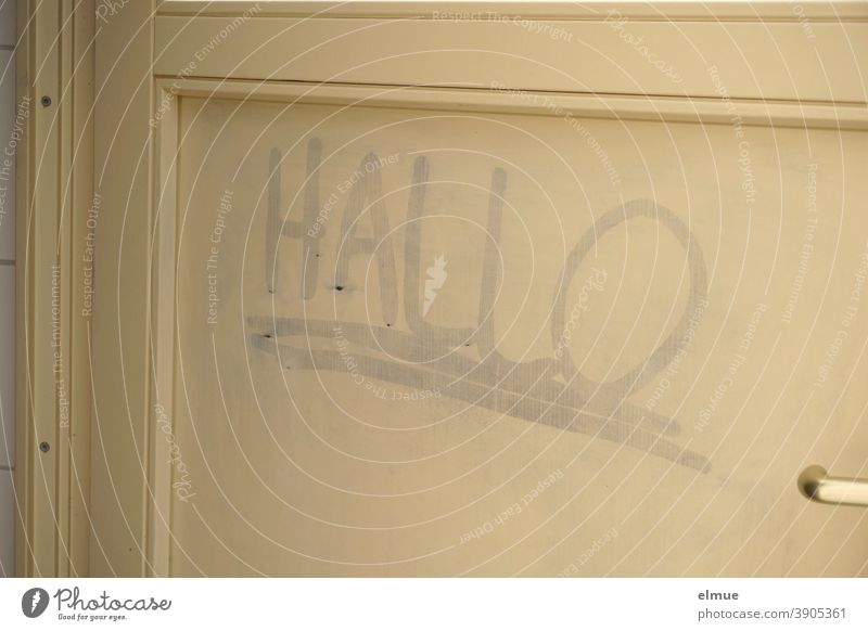 on a beige wooden door someone has written "HELLO" and underlined it twice / smearing / contact search Hello Wooden door Daub Word Contact search Youth culture