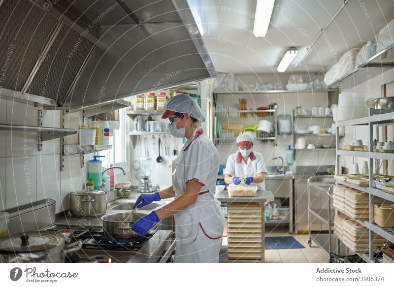 Kitchen staff in masks and gloves cooking food kitchen coronavirus prepare protect work pandemic colleague coworker covid 19 covid19 epidemic female job chef