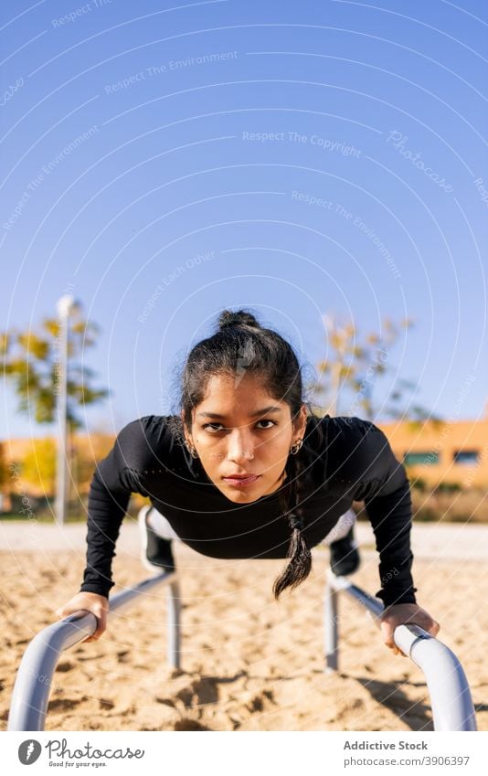 Sportswoman balancing on parallel bars workout exercise calisthenics gymnastic acrobatic athlete female ethnic practice sport training concentrate endurance