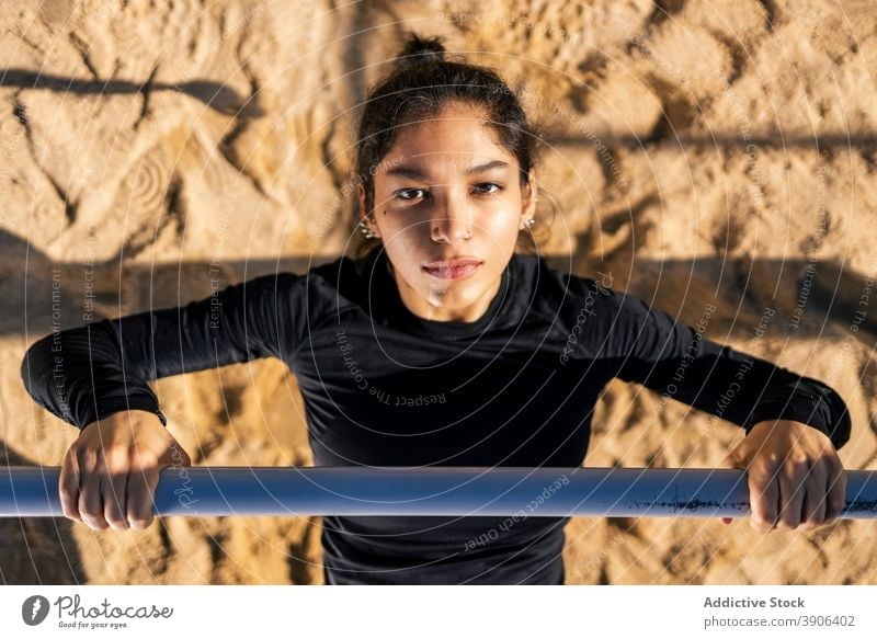Determined woman doing exercises on horizontal bar calisthenics sports ground strong determine athlete workout female ethnic practice fitness training