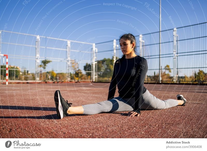 Flexible woman doing splits on sports ground exercise flexible stretch leg calisthenics training workout sportswoman female slender wellbeing practice fit