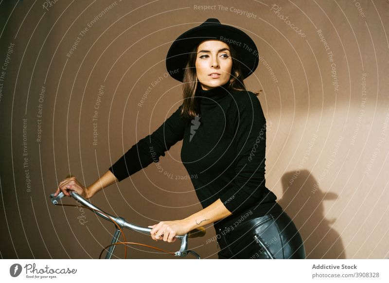 Stylish woman in hat standing near bicycle style trendy leather confident fashion slim young brunette attractive black female outfit appearance cool vogue