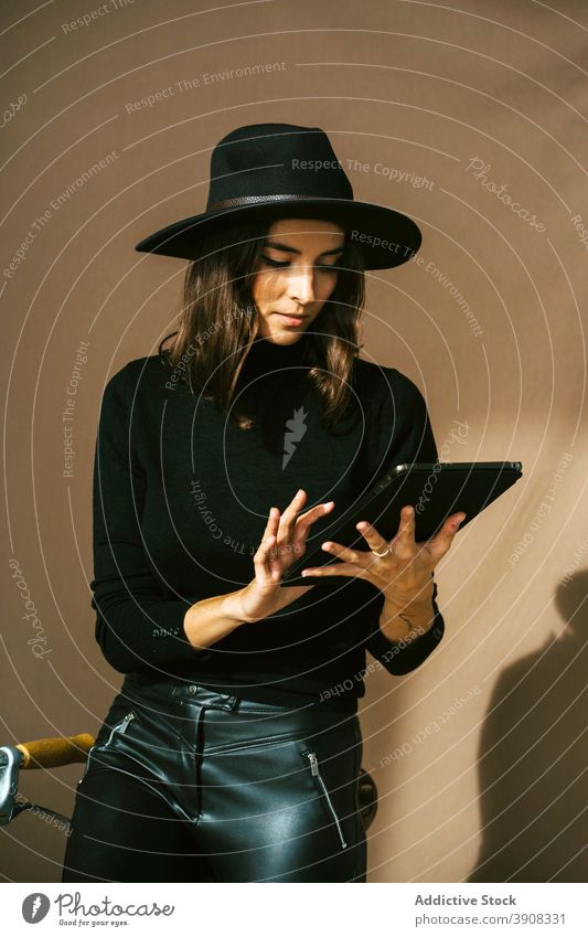 Woman in stylish black outfit using tablet near bicycle woman style trendy gadget device check bike traveler hipster lifestyle modern browsing female leather