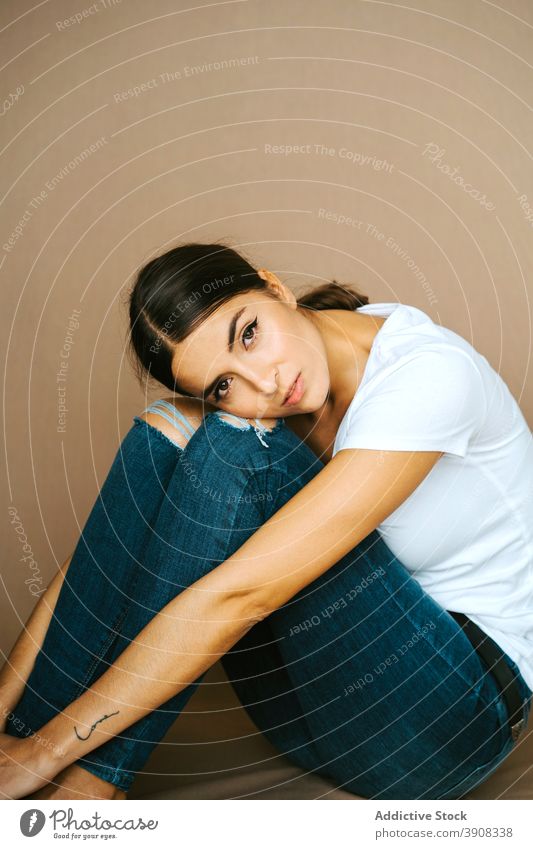 Tender woman in casual clothes in studio embracing knee tender outfit delicate appearance charming peaceful relax female floor gentle tranquil slim serene