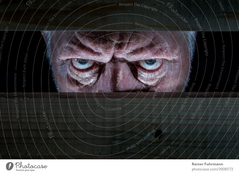 A man looks evil through a wooden barricade Man Evil portrait Eyes Human being Looking Face Fear Freak Force Aggression Aggravation Anger Dark Heartless