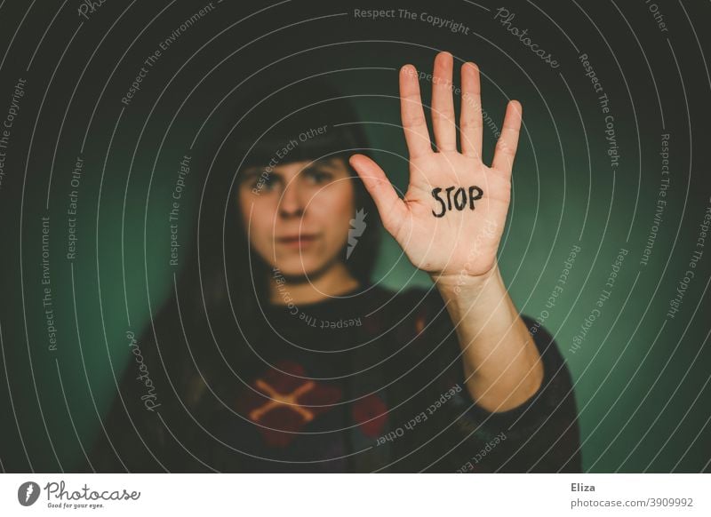 Woman stretches out her outstretched hand, on which the word Stop is written, into the camera. Saying no, showing boundaries. stop frontiers Hand Cancelation
