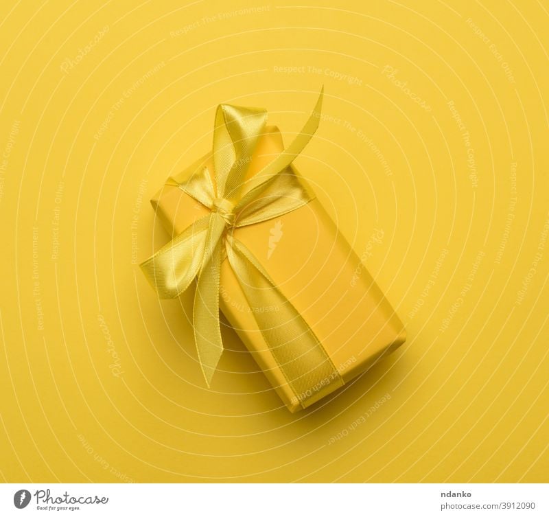rectangular box with a gift wrapped in yellow paper and tied with a silk yellow ribbon festive greeting holiday minimal new nobody package parcel present
