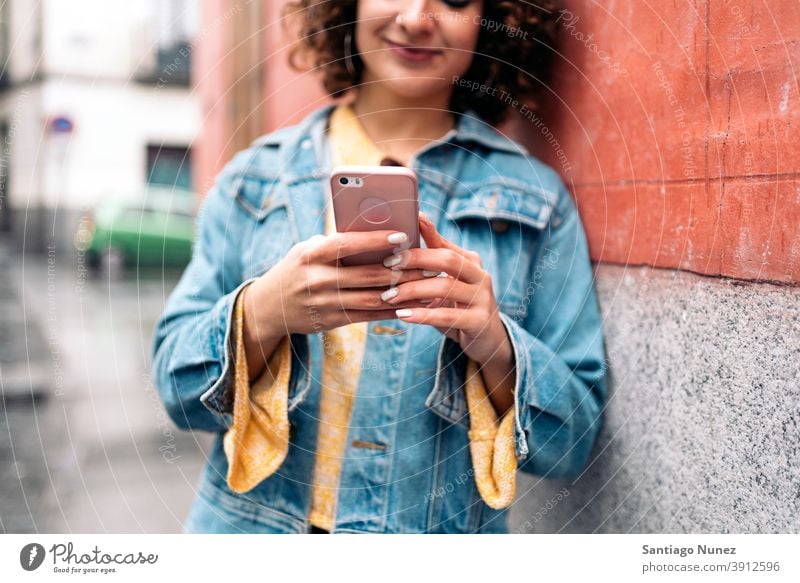 Young Woman Using Phone caucasian curly hair unrecognized faceless young woman using phone street city life smiling happy cellphone smartphone communication