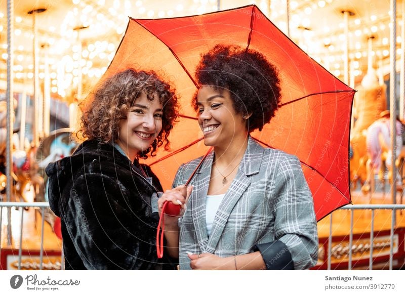 Happy Friends in Rainy Day umbrella rainy day friends afro girl black woman caucasian city life smiling front view portrait women looking at camera carousel
