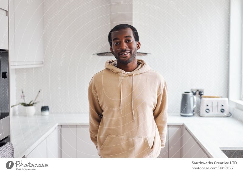 Portrait Of Smiling Young Man Standing In Kitchen Of New Home man young men house buying home new home first home moving in moving day indoors kitchen