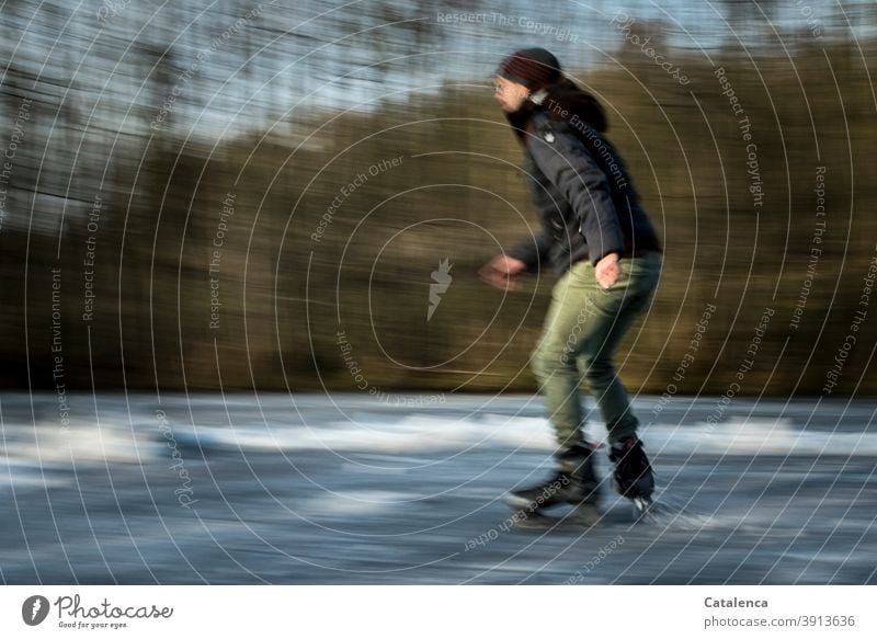 Young man skating on the frozen pond Athletic Lake trees Joy swift Cold and frost Ice Winter fun skates ice skating Landscape Tree Green Gray winter jacket Cap