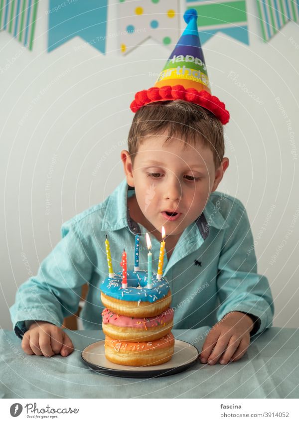 Child blows out the candle on birthday donuts cake boy hands five year his little child hold plate doughnut fun five-year-old happy sprinkles food sweet dessert