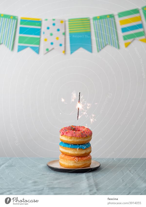 Birthday donuts cake with sparkler on table bengal light birthday garland birthday donuts stack sweet delicious doughnuts party flag background vertical copy