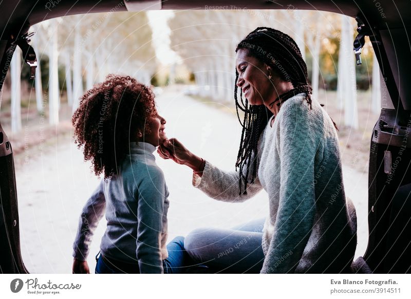 hispanic mother and afro kid girl sitting in a car in nature. Autumn season. Family and travel concept portrait daughter family outdoors mixed race motherhood