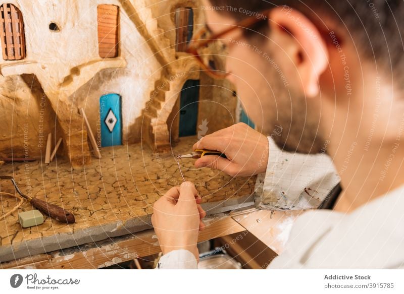 Crop artisan creating model of clay house in studio workshop man building miniature create door male hobby facade professional skill craft concentrate talent