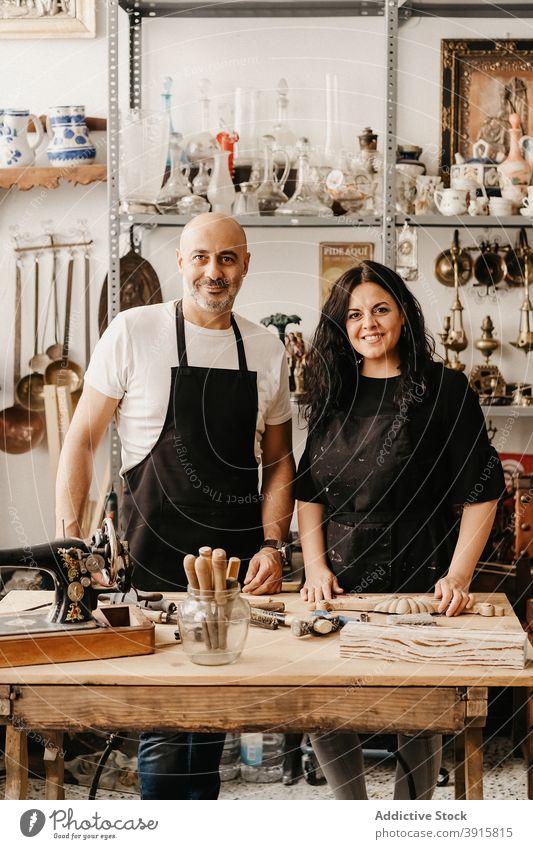 Cheerful couple of artisans standing at workbench in art studio carpenter craft together workshop smile professional small business friendly creative job