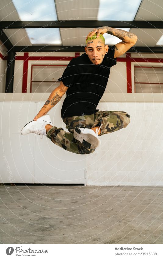 Energetic break dancer jumping high man leap energy move perform fly acrobatic style young male activity lifestyle skill modern practice talent tattoo agile