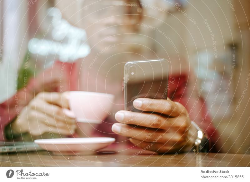Black man using smartphone in cafe chill browsing coffee relax weekend drink coffee shop male ethnic black african american table hat device gadget beverage