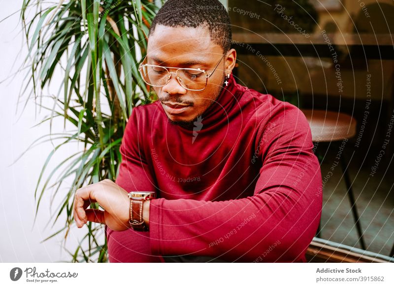 Black man checking wristwatch in city time wait time management accessory accuracy punctual male ethnic black african american expensive outfit appointment