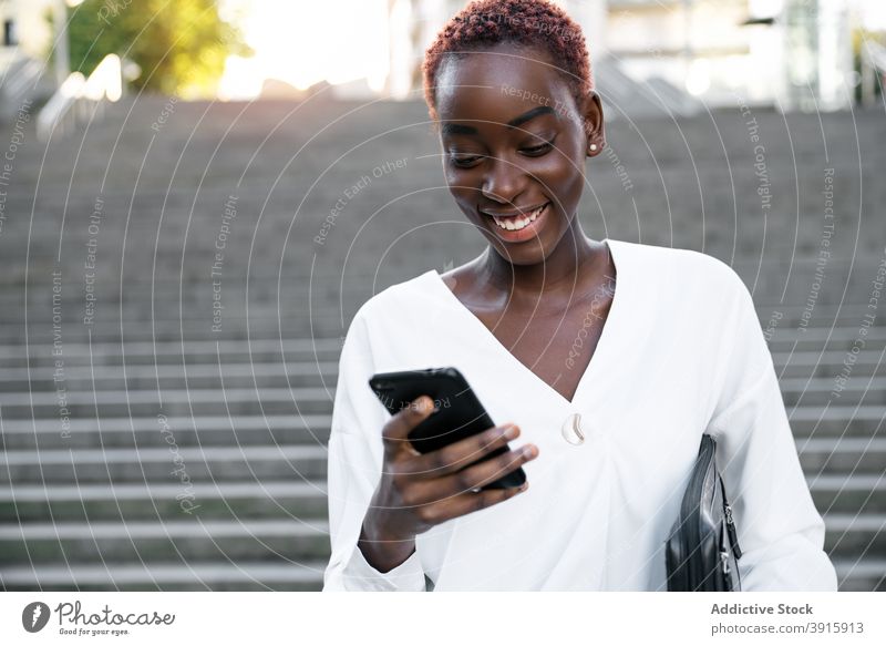 Cheerful black woman using smartphone on city street businesswoman happy read urban style mobile smile satisfied modern young african american ethnic female