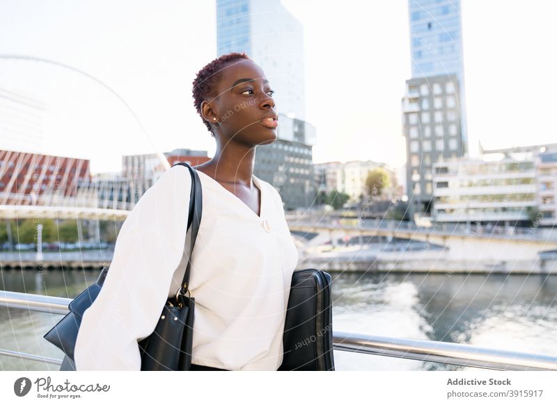 African American businesswoman standing on city embankment confident positive modern urban style success happy young black african american ethnic short hair