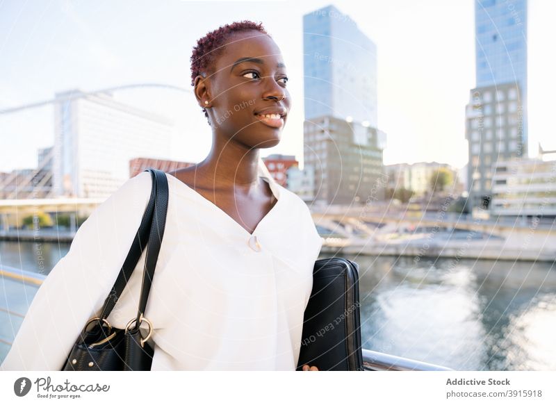 Smiling African American businesswoman standing on city embankment confident positive modern urban style success happy young black african american ethnic
