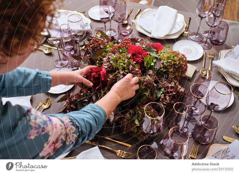 Anonymous woman setting table with flowers at home table setting festive event housewife floral female decor bloom occasion bouquet prepare celebrate blossom