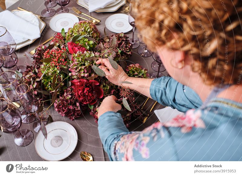 Anonymous woman setting table with flowers at home table setting festive event housewife floral female decor bloom occasion bouquet prepare celebrate blossom