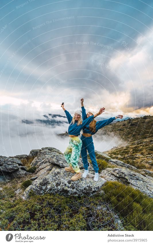Carefree women on rock in mountains traveler together carefree freedom enjoy arms raised scenery vacation spectacular highland female nature tourism journey