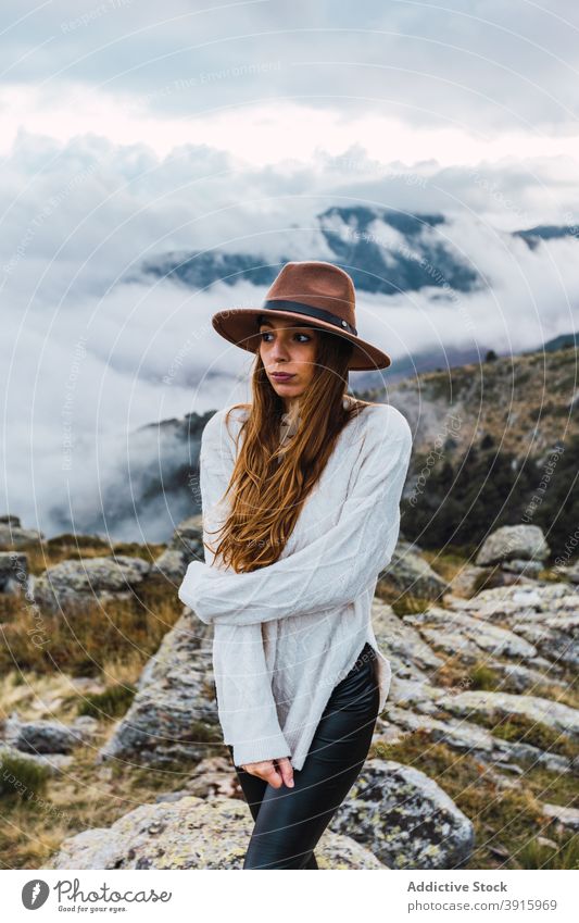 Delighted woman jumping on stones in highlands carefree mountain freedom vacation traveler explore female nature journey rock hat adventure summer trip holiday
