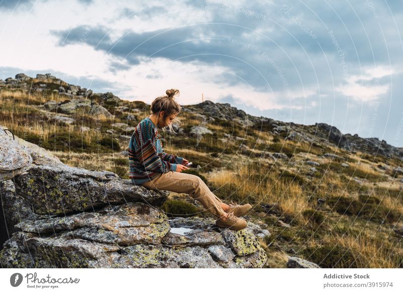 Traveling woman browsing smartphone in highlands mountain trekking hiker break relax traveler female rough rock using tourist gadget tourism wanderlust nature