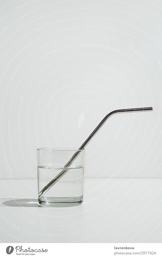 Transparent glass of water on white with sustainable metal straw drink eco friendly beverage cool cold healthy thirsty freshness ingredient refreshment