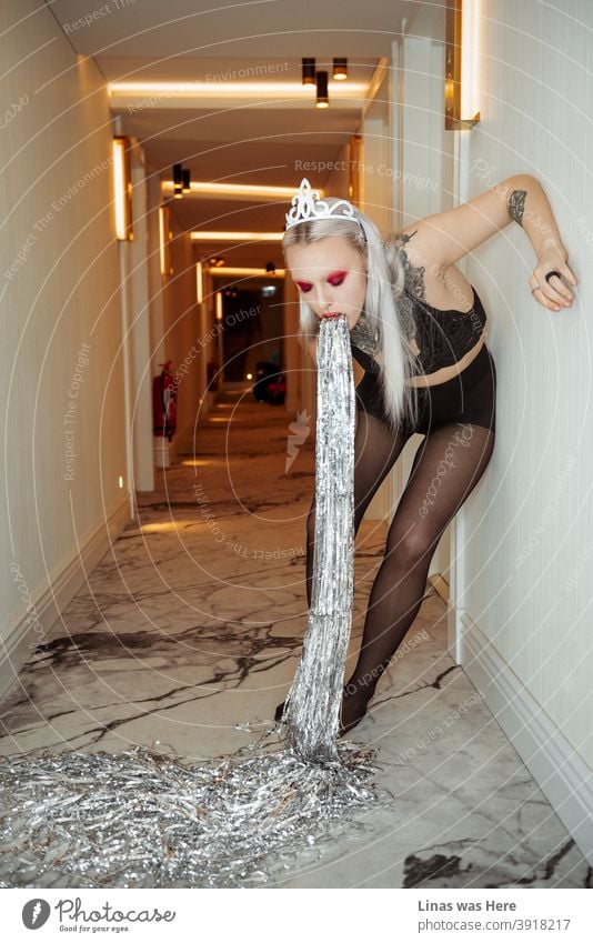 A gorgeous inked girl in a corridor of the hotel vomiting confetti. Sometimes too much joy during the holidays can make you sick. garlands tattoos makeup