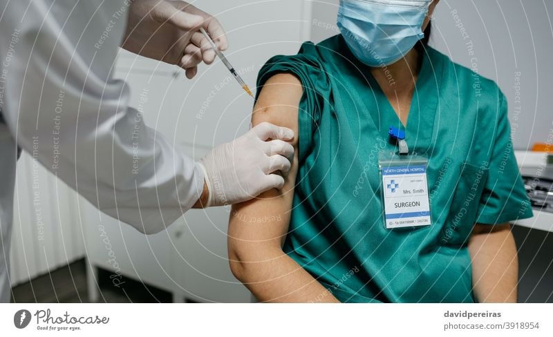 Unrecognizable female surgeon receiving coronavirus vaccine health workers unrecognizable injecting doctor priority group covid-19 closeup arm health personnel