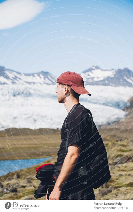 Man looking a glacier Guy Portrait photograph Cap Hat Red Camera Iceland Nature Looking Glacier Cold Sky Snow