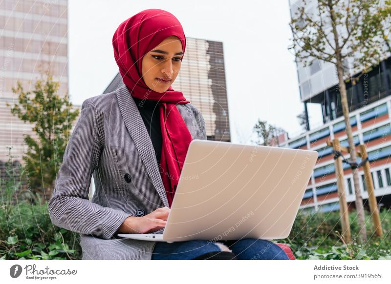 Ethnic female freelancer in hijab working on laptop in city woman entrepreneur headscarf street businesswoman ethnic arab project internet using modern