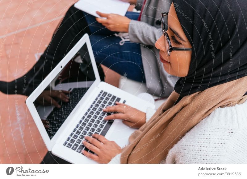 Ethnic women in hijab studying in campus muslim student prepare exam exam preparation learn female ethnic arab bench green garden headscarf device netbook