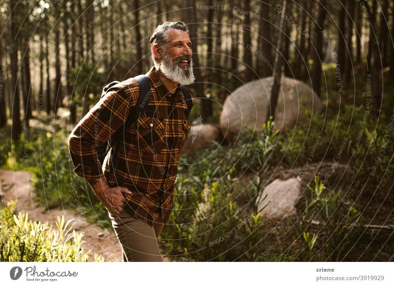 Happy Senior man smiling on hike in forest hiking sunny senior retirement adventure fun happy wellbeing walking lifestyle leisure laughing positive hipster
